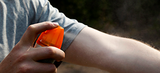 Man spraying insect repelent on arm
